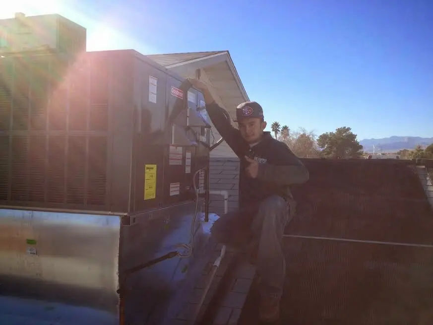 HVAC technician performing Air Duct Repair on a rooftop unit in Safford