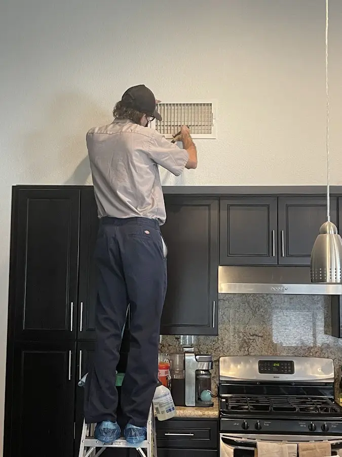 Technician inspecting an air vent during HVAC service in Safford